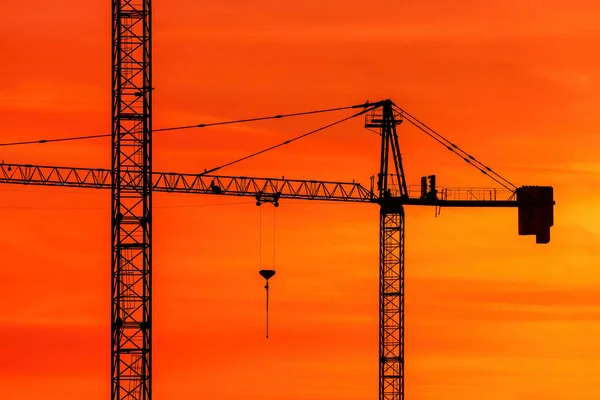 Silueta Stavebních Jeřábů Proti Jasně Oranžové Obloze Západu Slunce Průmyslovým — Stock fotografie