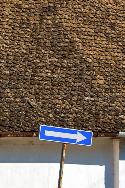 单行道欧洲交通标志 蓝色路面上有白色箭头 背景为老式屋顶瓷砖图案 有选择焦点 — 图库照片