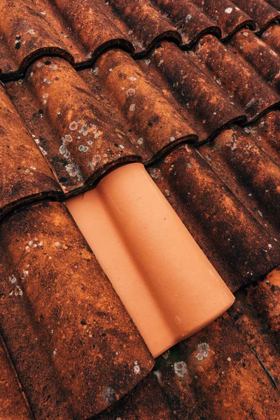 来自克罗地亚洛夫兰的单个新的黏土屋顶瓦 以旧旧的乡村梯形屋顶为背景 — 图库照片