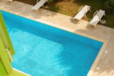 Güneşli yaz gününde apartmanın penceresinden boş yüzme havuzunun yüksek açılı görüntüsü