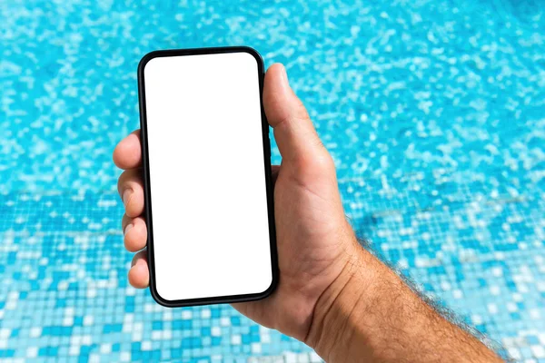 夏にはきれいな屋外スイミングプールの水の上に空白のモックアップ画面と携帯電話を保持男 選択的フォーカス — ストック写真