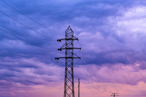劇的な紫色の日没の空に対するエネルギー危機状況の概念的なイメージ 電気パイロンと電源ラインケーブルのシルエット 選択的な焦点 — ストック写真