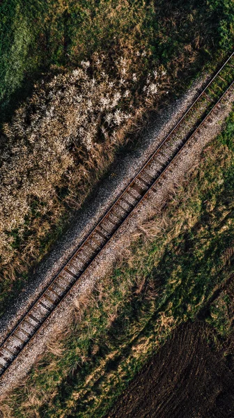 春の耕作された田園風景を介して実行されている鉄道線路の空中ショット 高角度ビュー ドローンのPov — ストック写真