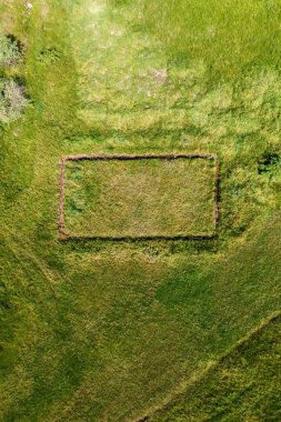 İHA pov 'dan çimenlikteki bitmemiş evin hava görüntüsü, sosyal medya arkaplan resmi olarak çayırda dikdörtgen şeklinde şekil, üst görünüm