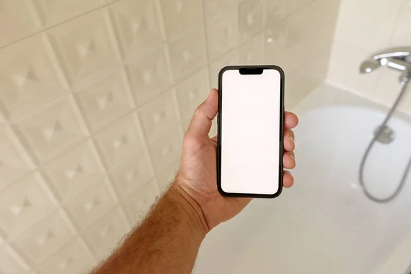 浴室里的智能手机模型 男人在浴缸里拿着带有空白触摸屏的手机 选择焦点 — 图库照片