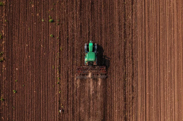 播种季节前配以耕地机进行田间耕作的绿色拖拉机车辆 从无人驾驶飞机顶部俯冲而下 — 图库照片