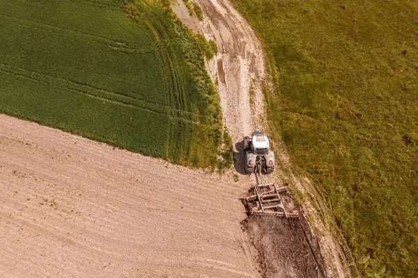 田への未舗装道路の運転に添付されたティラーと農業トラクターの空中ビュー ドローンのPov高角度ビュー — ストック写真