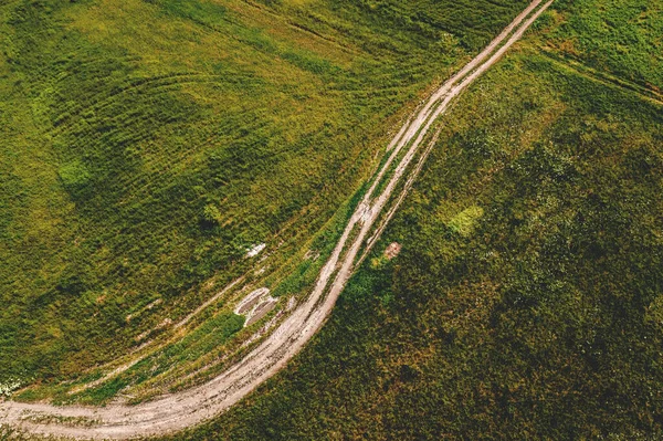 緑の芝生の牧草地を介して湾曲した未舗装の道路の空中ショット ドローンのPov高角度ビュー — ストック写真