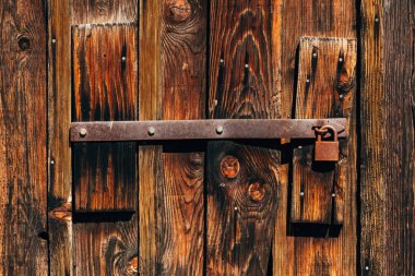 Arka plan olarak ahşap çiftlik ambarı kapısında paslanmış eski asma kilit.