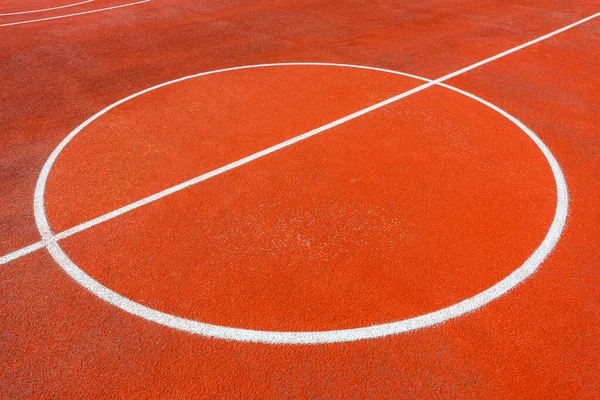 Minimalist abstract background of an orange tartan outdoor basketball court with white lines. Selective focus.