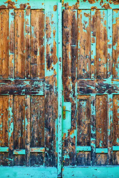 金属のハンドルが付いている青いペンキの皮をむく古い木製のゲートの戸口 — ストック写真