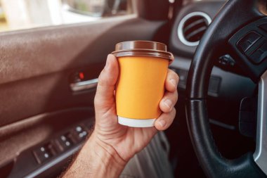 Paket kahve, arabada sarı kahve bardağı tutan adam, seçici odaklı pov imajı.