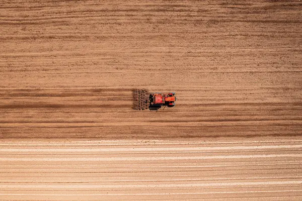 播种季节前 带有耕作机的红色农用拖拉机进行田间耕作 从无人驾驶飞机顶部俯冲而下 — 图库照片