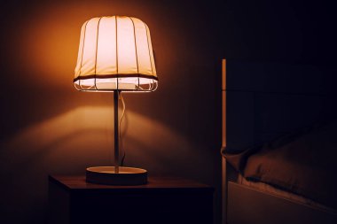 Nightstand bedside lamp in bedroom at night, selective focus clipart