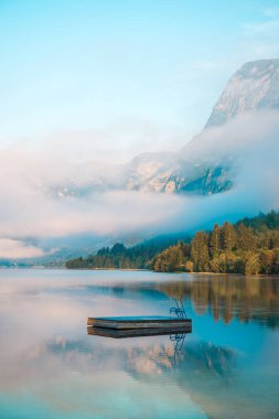 Yaz sabahı Bohinj Gölü 'nde küçük yüzen iskele, seçici bir odak noktası.