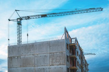 Tall prefabricated residential building construction site with old crane, selective focus clipart