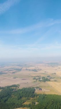 Kabarık beyaz bulutların uçaktan, yüksek açılı manzarayla ekilmiş düz arazi üzerindeki hava görüntüsü. Dikey çekim.