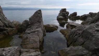 Kvarner gulf of Adriatic sea rocky coastline, large rocks at shoreline in old town of Lovran in Croatia. Selective focus.