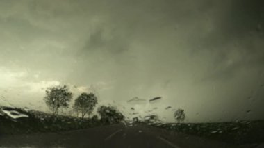 Fırtınalı bir yağmurda yol boyunca araba sürmek, yağmura batırılmış ön cam ve otoyolun kamera görüntüleri, seçici bir odak noktası.