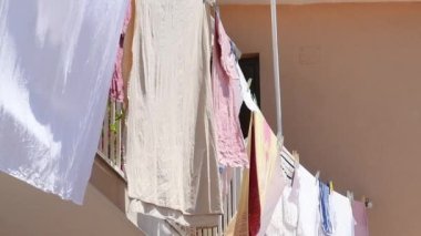 Güneşli bir yaz öğleden sonrasında açık havada çamaşır ipinde kuruyan mutfak havluları, ağır çekimde.