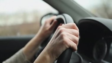 Kadın sürücü ülke yolunda araba sürüyor, direksiyondaki ellere yakın çekim, 4K görüntü.