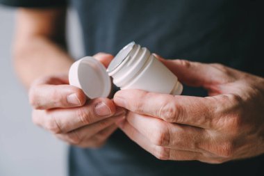 Plastik ilaç kavanozu ile erkek ellerine yakın çekim, seçici odaklanma
