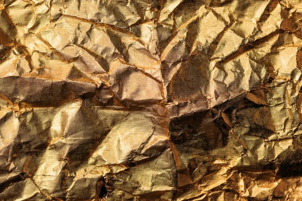 Crumpled gold colored aluminum tin foil texture as background, top view