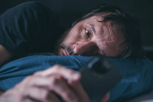 男人在深夜躺在床上用智能手机 失眠的概念 有选择的专注 — 图库照片