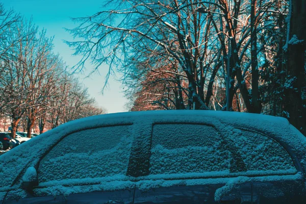 Frozen snow-covered car on parking lot in winter morning, selective focus