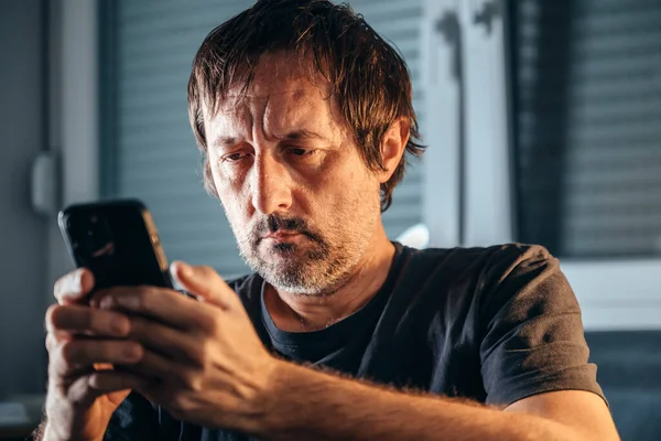 男人在室内用手机 单独一个成年人拿着智能手机 有选择地集中注意力 — 图库照片