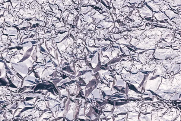 Crumpled aluminum tin foil texture as background, top view