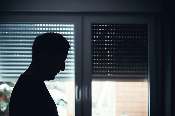 抑郁和悲伤 精神健康的概念 沮丧绝望的男人站在窗边 拉下百叶窗的轮廓 有选择的重点 — 图库照片