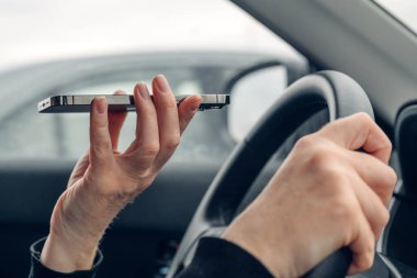 Araba kullanan ve cep telefonuyla konuşan bir kadın, onu ağzının önünde tutarken, iletişim teknolojisi ve ulaşım, seçici odaklanma