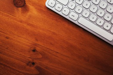 Kahverengi ofis masasında modern beyaz metalik kişisel bilgisayar klavyesi, kopya alanı ile üst görünüm