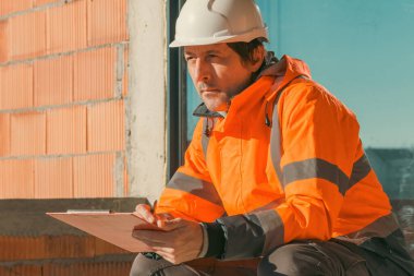 İnşaat müteahhiti ve inşaat mühendisi inşaat sahasına çizimler yapıyor ve notlar yazıyor, seçici odaklanma