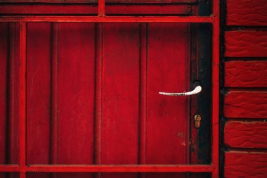 Aşınmış sapı ve kilidi olan eski kırmızı metalik kapı.