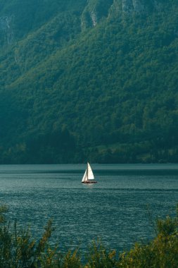 Slovenya 'daki Bohinj Gölü' nde yelkenli sürerken, tanınmayan insanlar yaz aylarında suyun keyfini çıkarıyorlar.