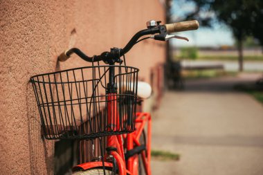 Caddedeki klasik kırmızı bisiklet. Duvara yaslanmış, seçici bir odak noktası var.