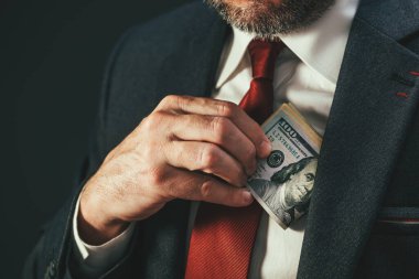 Siyaset ve rüşvet, yozlaşmış politikacı takım elbisesinin cebine para koyuyor, seçici odaklanma.