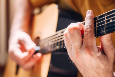 Evde akustik gitar çalan erkek ellerinin yakın çekimi, seçici odaklanma