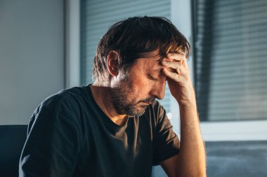 Evde gözleri kapalı, yalnız ve depresif bir yetişkin adam. Traşsız erkek üzgün ve mutsuz. Akıl sağlığı ve pişmanlık kavramı. Seçici odak.