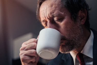 İşadamı gece geç saatlere kadar çalışırken ofiste kahve içiyor. Projenin son teslim tarihini karşılıyor. Seçici bir odak noktası.