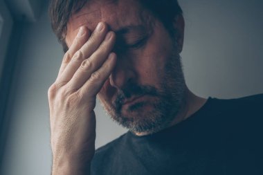 Karanlık odanın içindeki umutsuz, hayal kırıklığına uğramış adam, seçici bir odak