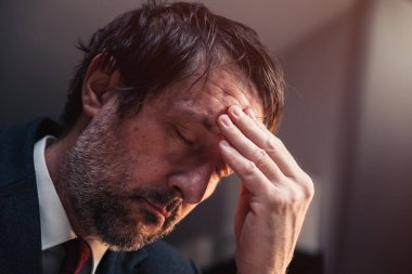 Stresli ve endişeli işadamı, gece geç saatlere kadar çalışırken kendini kötü ve yorgun hisseder.