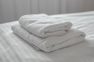 Otel yatağında katlanmış temiz beyaz havlular, seçici odak
