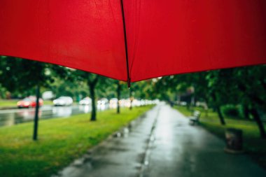 Yağmurlu bir günde kırmızı şemsiyeyle cadde ve kaldırım manzarası, seçici odaklanma