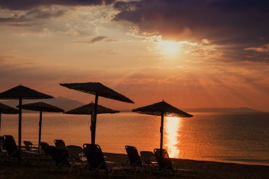 Reed sun umbrellas at beach in Vrasna, silhouette of seaside tourist resort parasol in summer sunrise, selective focus clipart