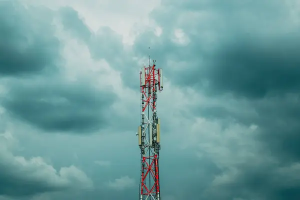 Stock image Mobile telephony signal repeater tower against overcast cloudy sky, selective focus