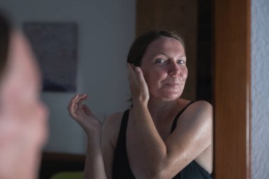 Kadın evde yüzüne güneş losyonu sürüyor, seçici odaklanma.