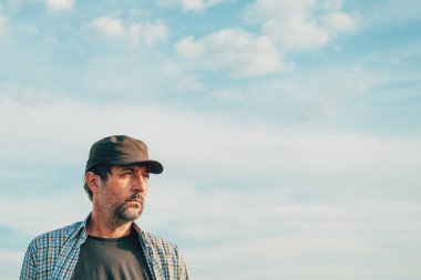 Kamyon şoförü şapkası takan erkek tarım uzmanının portresi güneşli yaz gökyüzüne karşı, seçici odaklanma